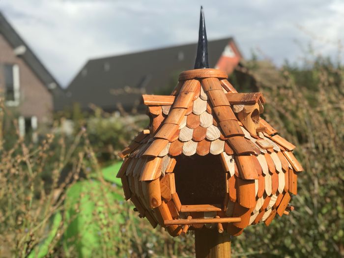 Close-up of a birdhouse with roof tiles on the field