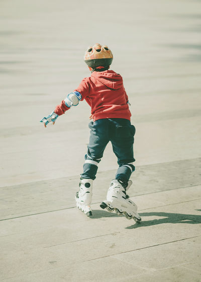 Rear view of boy roller skating on footpath