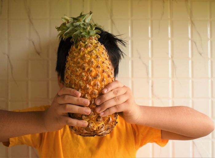 Midsection of boy holding pineapple
