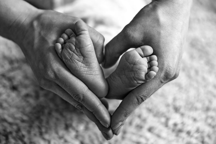 Close-up of father holding baby legs at home