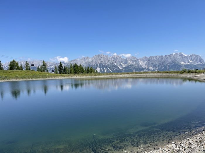 Scenic view of lake and mountains against clear blue sky