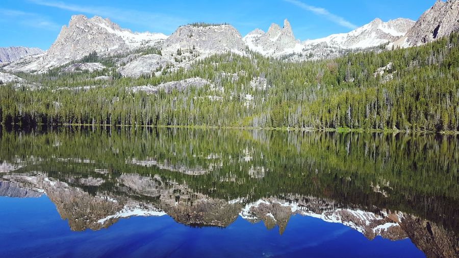 Reflection of trees against snowy mountains on hell roaring lake