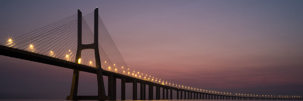 Low angle view of vasco da gama bridge against sky at sunset