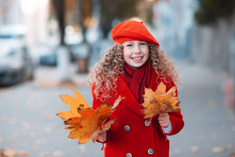 Stylish happy kid girl 5-6 year old with blonde curly hair wear red color jacket and beret hat 