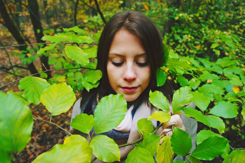 Close-up of woman amidst leaves in forest