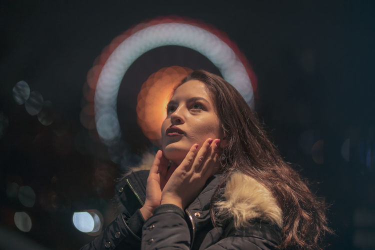 Close-up of thoughtful young woman wearing warm clothing at night