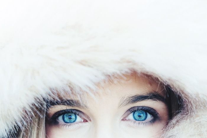 Cropped image of woman with blue eyes wearing fur hood