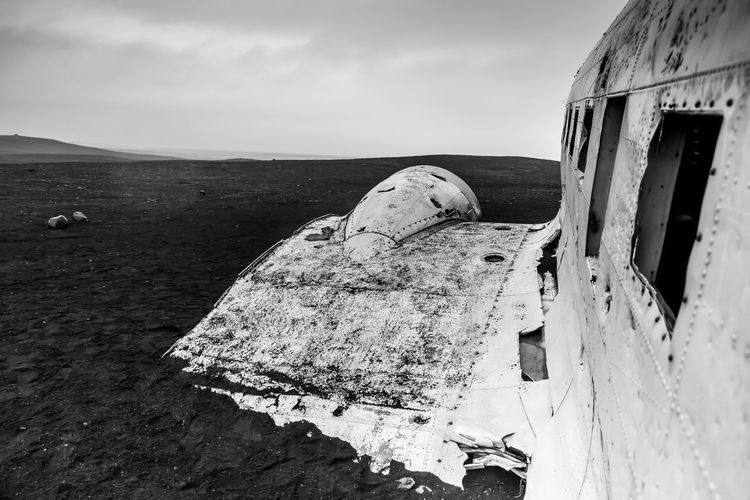 Airplane wreckage at solheimasandur beach against cloudy sky