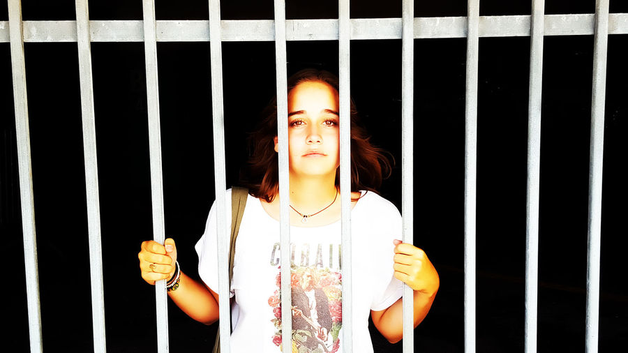 Portrait of beautiful woman standing behind security bars