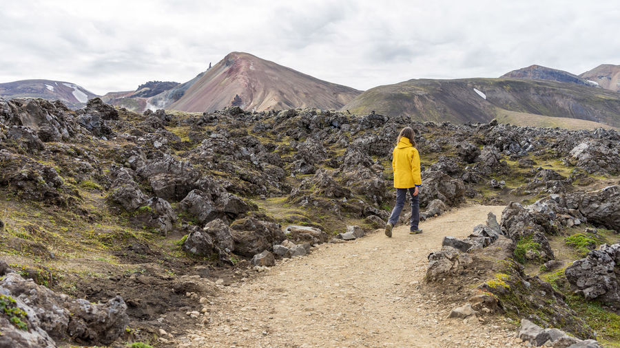 Young woman is hiking down landmannalaugar rocky trail in iceland