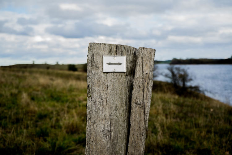 Wooden post on field against sky