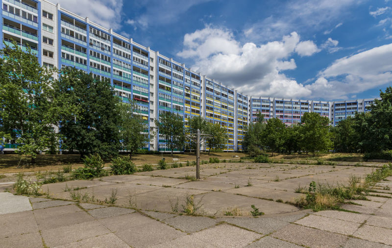 Empty park by buildings in city against sky