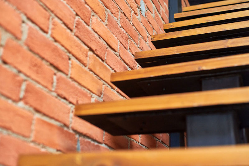 Close-up of wooden staircase against brick wall