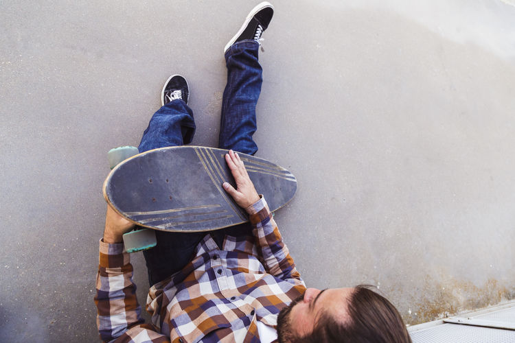High angle view of man holding skateboard sitting outdoors