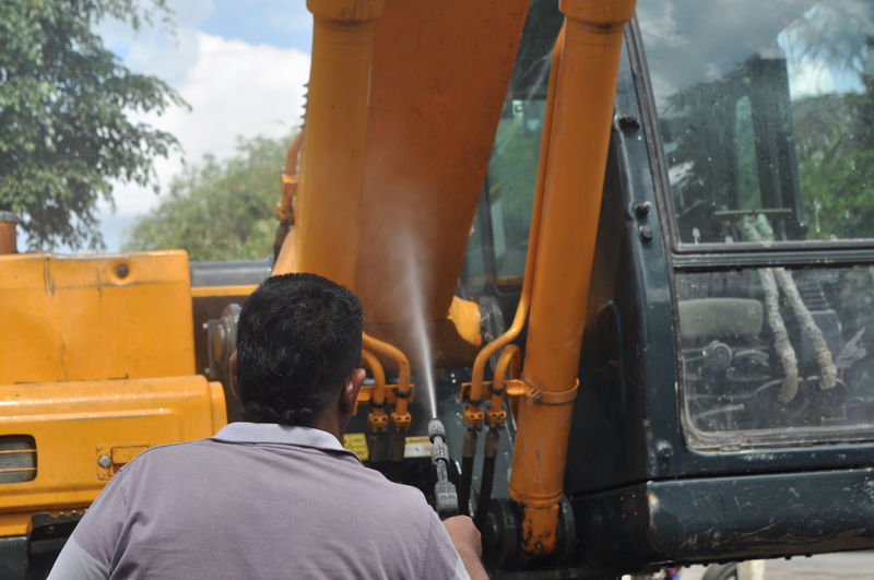 Rear view of man working at cleaning excavator construction site