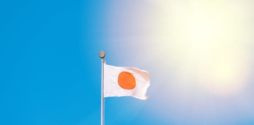Low angle view of japanese flag against blue sky