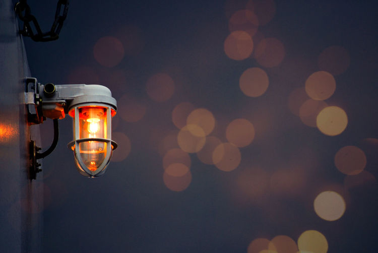 Close-up of illuminated lamp hanging on street light