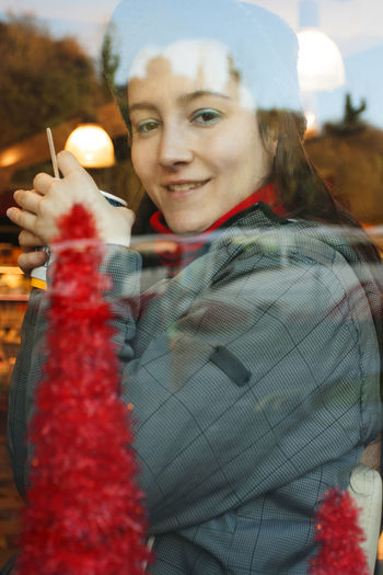 Portrait of smiling young woman seen through glass