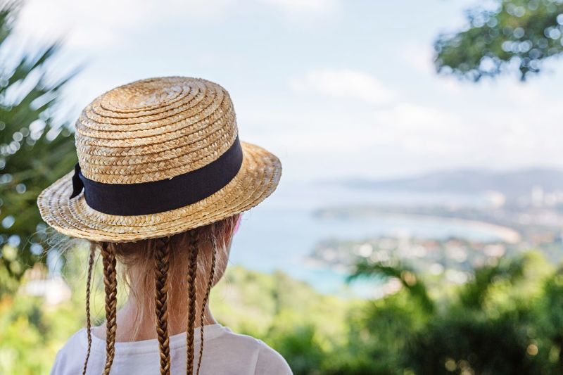 Rear view of girl in hat against sky