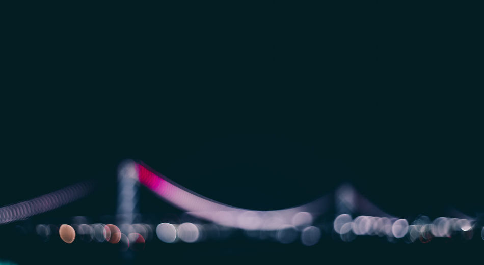 Defocused image of illuminated bridge against clear sky at night