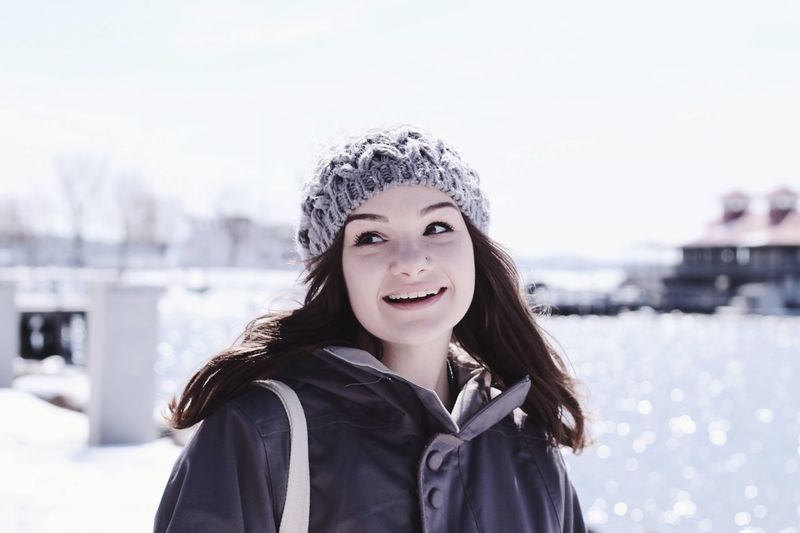 Smiling woman in warm clothing on snow covered field against sky