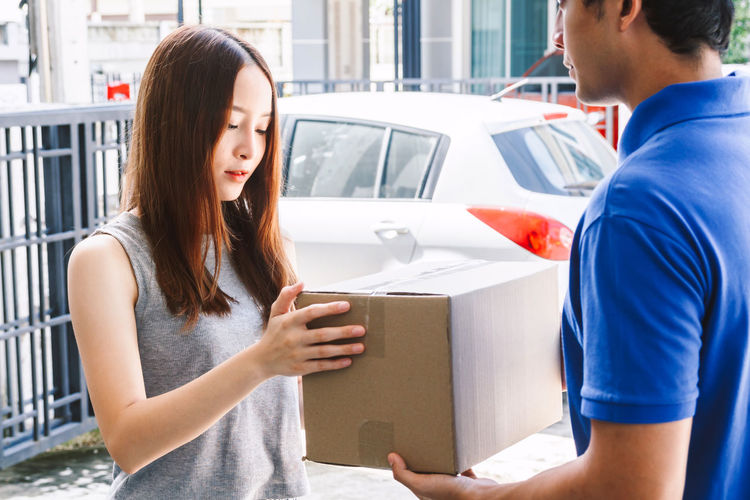 Woman receiving package from salesman while standing at doorway