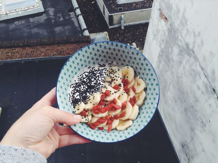 Cropped image of hand holding bowl of fruits