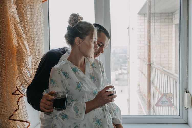 Woman looking away while sitting on window