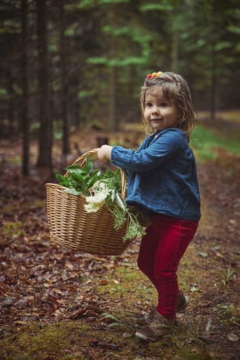 Charming baby collects medicinal herbs in the forest