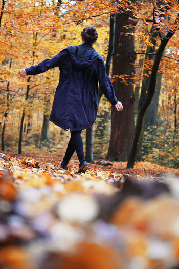 Full length rear view of man walking on autumn leaves