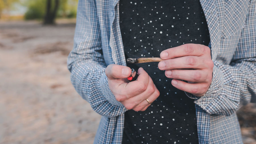 Midsection of man holding marijuana joint