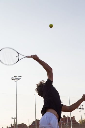 Man playing tennis on court against clear sky