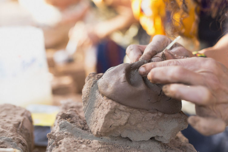 Cropped hands of woman mixing mud