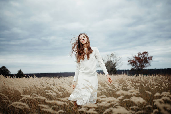 Portrait of woman walking on field against sky