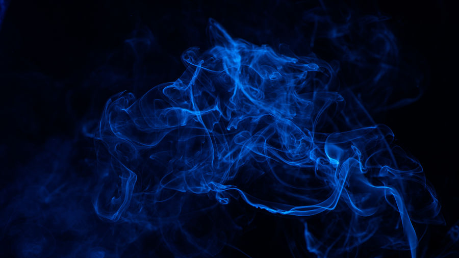 Conceptual image of blue color smoke isolated on dark black background, halloween concept design.