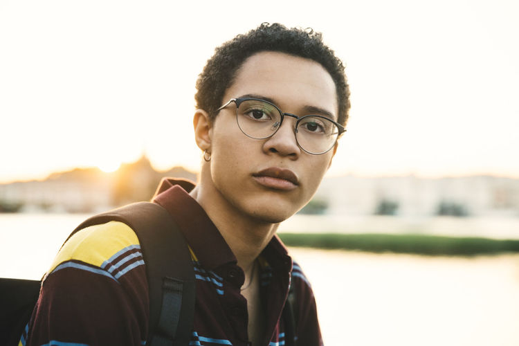 Portrait of young man wearing eyeglasses against sky