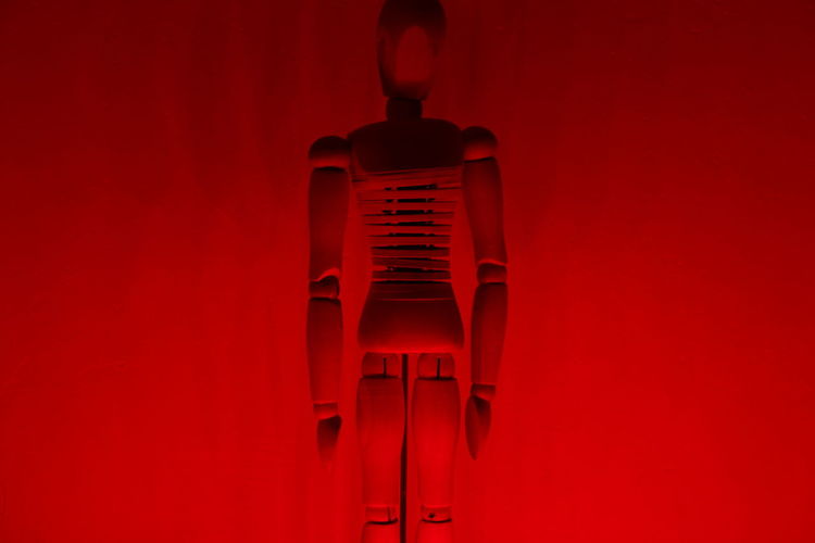 Close-up of wooden figurine against red wall