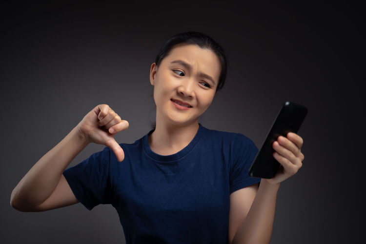 Portrait of teenage girl using smart phone against black background