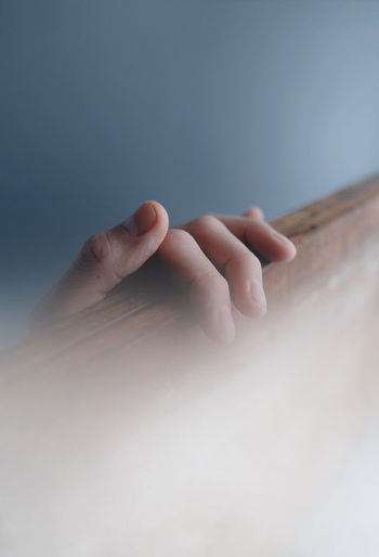 Close-up of human hand  on wood board in fog