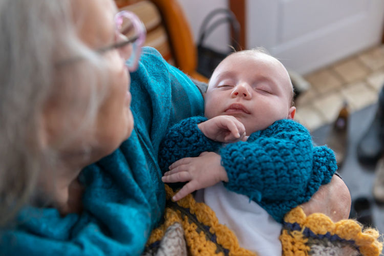 Grandmother holding baby in hand at home