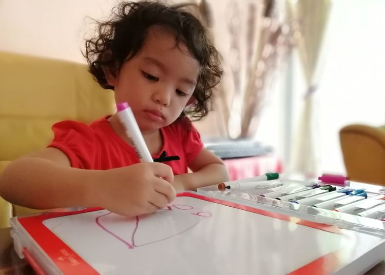 Girl drawing on book at home