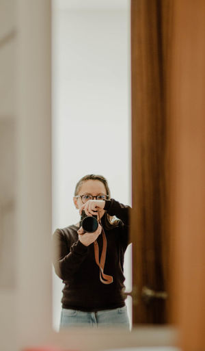Portrait of woman holding camera at home