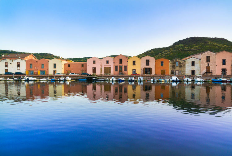 The colorful old buildings of bosa reflected on the temo river at sunset, sardinia