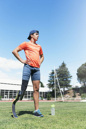 Low section of athlete with prosthetic leg standing on field