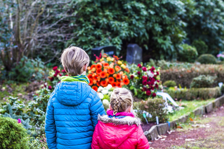 Siblings standing against flowers in graveyard