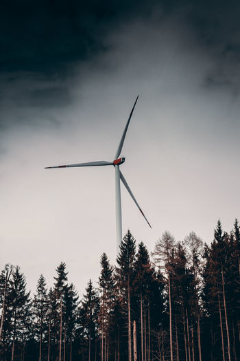 Low angle view of wind turbines against sky