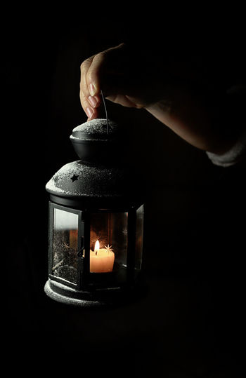 Person holding lit candle in the dark
