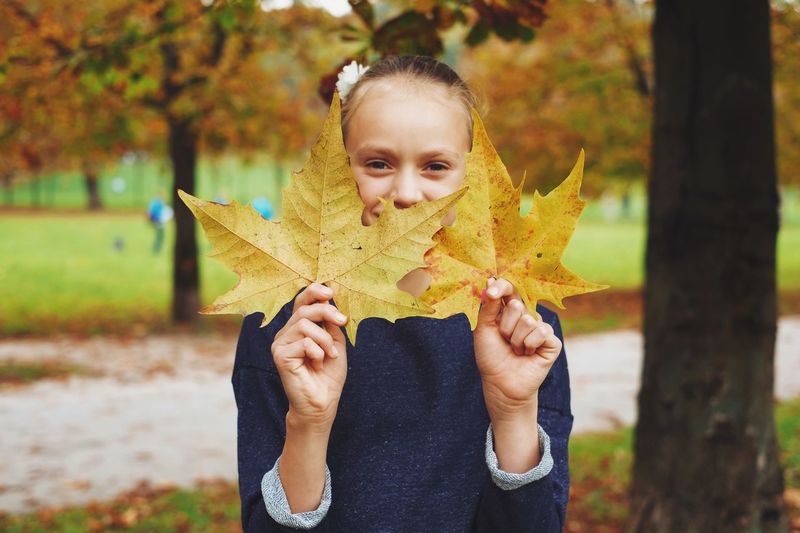 Young woman holding leaves in park
