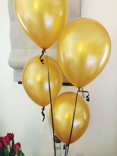 Low angle view of golden balloons against wall