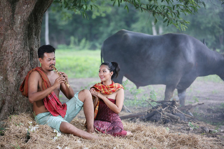 Couple sitting by tree outdoors